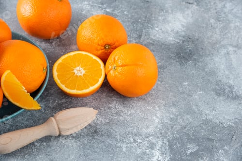 Preview: A bowl full of sliced and whole juicy orange fruits with wooden reamer