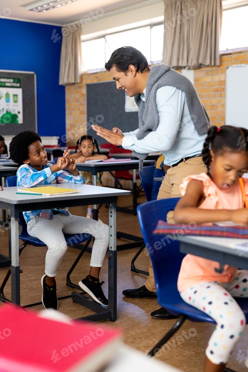 Preview: Diverse male teacher teaching school boy using sign language in class at elementary school