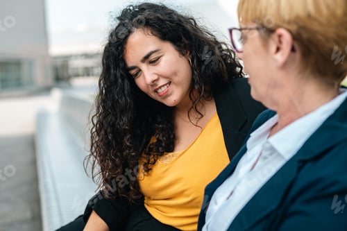 Preview: Two co workers chill during their free spare time in a park sharing ideas and stories. Showing phone