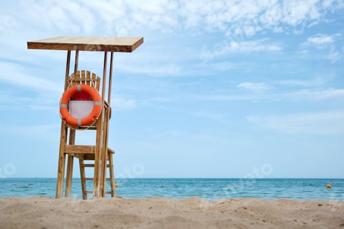 Preview: Emplty wooden lifeguard station on sandy beach on ocean shore in summer