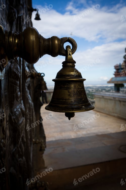 Preview: Vertical shot of an antique bell hanging on a wall with blurred background