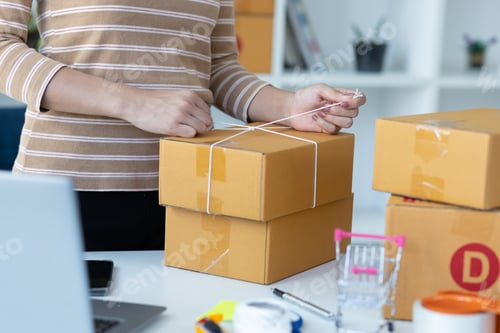 Preview: Small start-up business woman working with parcel boxes packing goods in preparation for delivery.