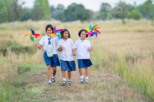 Preview: Group of little Asian girls hold small windmill and look fun to run together in walkway rice field