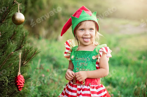 Preview: Child waiting for a Christmas in wood in july. portrait of little children near christmas tree.