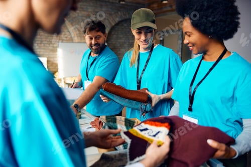 Preview: Multiracial group of people sorting clothes while working as volunteers at community center.