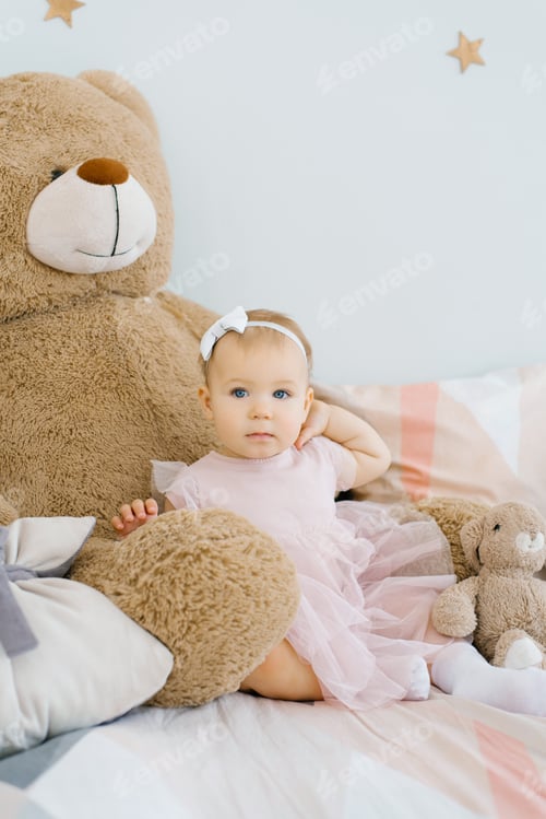 Preview: Cute One Year Old Baby Sits Surrounded by Soft Animals Toys and Holds her Hand on her Neck