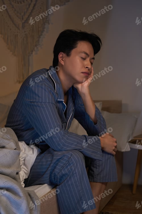Preview: Asian man having moments of reflection in a modern apartment at dusk