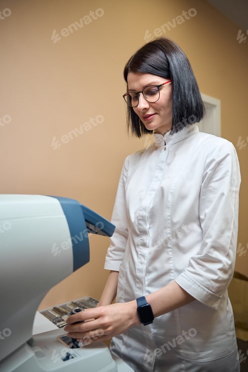 Preview: Woman ophthalmologist at her workplace, she adjusts a special apparatus