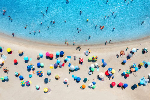 Preview: Aerial view of colorful umbrellas on beach, people in blue sea