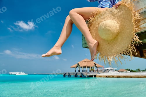 Preview: Woman sitting at beach jetty
