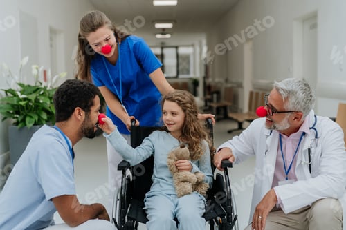 Preview: Happy doctors with clown red noses taking care about little girl.