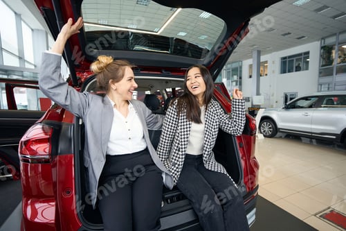 Preview: Happy ladies look at each other sitting in car trunk