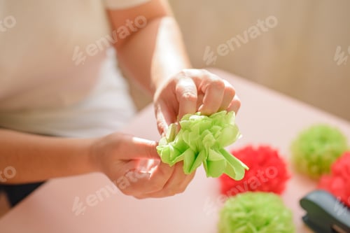 Preview: Female hands distributing petals on a green paper flower from napkins, close-up.