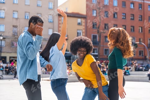 Preview: Multiethnic young friends dancing a city square, group of happy people having fun together