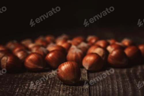 Preview: close up view of hazelnuts on wooden surface on black background