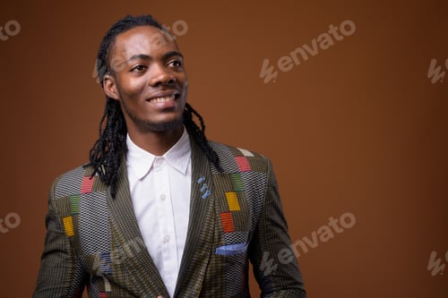 Preview: Young handsome African businessman against brown background