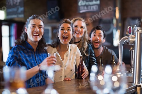 Preview: Cheerful friends standing by bar counter