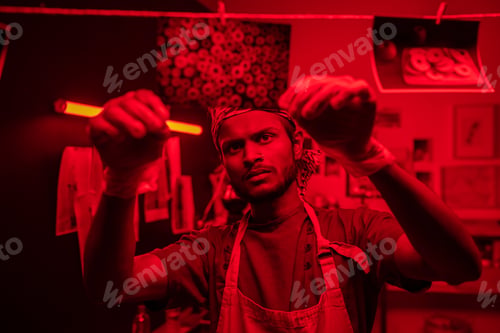 Preview: Young serious photographer hanging wet developed photos on thread