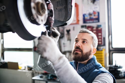 Preview: Man mechanic repairing a car in a garage.