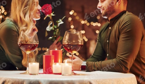 Preview: Holding beautiful red rose. Young lovely couple have romantic dinner indoors together