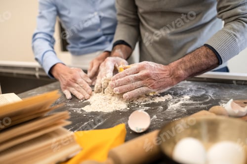 Preview: Hands working together kneading dough on a floured surface.