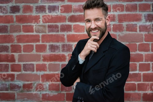 Preview: Portrait of a handsome young man standing against a brick wall outside