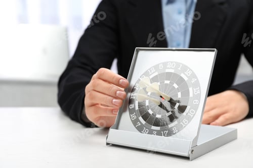 Preview: Woman with darts at table. Business trainer concept