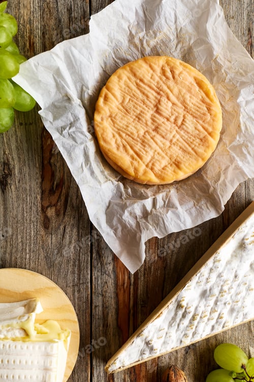 Preview: Delicious cheese brie or camembert with bunch of grape on wooden table.