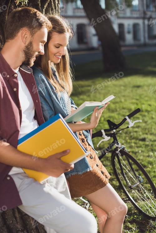 Preview: couple of young students reading homework in park