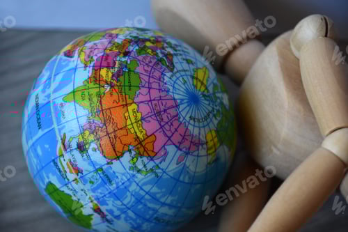 Preview: Wooden human figure holding globe planet Earth, world economic crisis