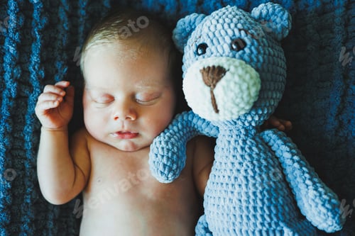 Preview: A newborn baby sleeps with a knitted teddy bear. Children's knitted toys. Baby sleep