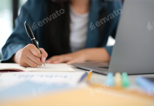 Preview: A woman is writing in a notebook with a pen