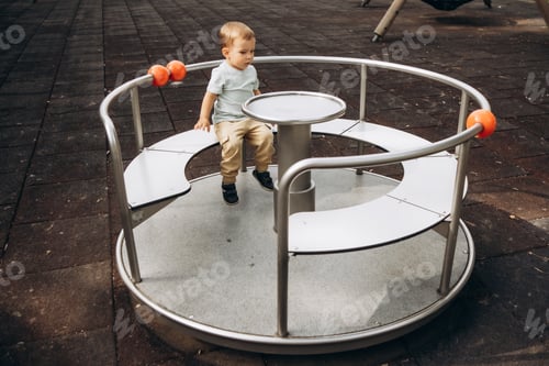 Preview: child is spinning on a children's carousel in the playground