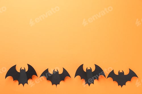 Preview: Halloween decor. Black paper bats on orange background, flat lay. Space for text