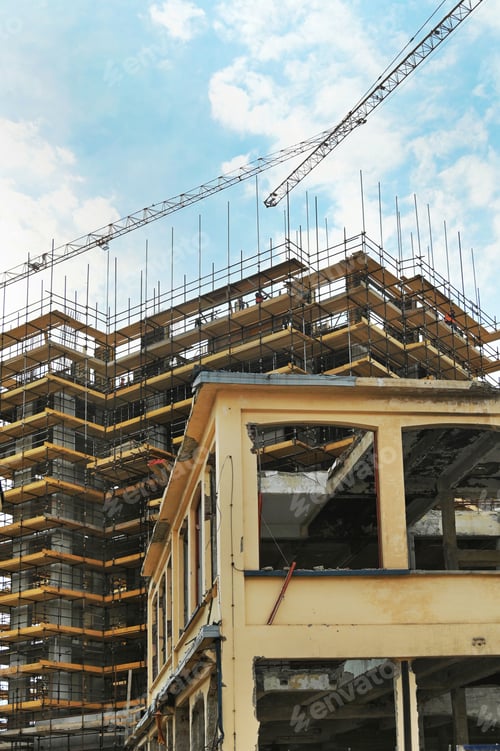 Preview: Vertical shot of a construction site with huge scaffolding and cranes around the buildings
