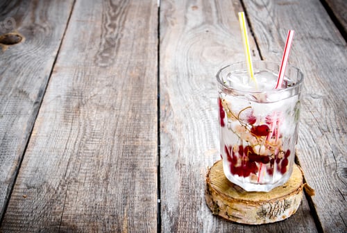 Preview: Cocktail of wild currant with ice on a wooden table. Free space for text.