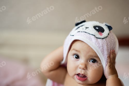 Preview: Adorable baby with a panda hooded towel looking curious