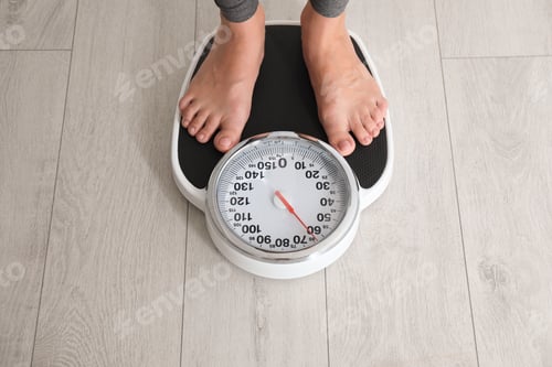 Preview: Woman standing on scales indoors. Overweight problem