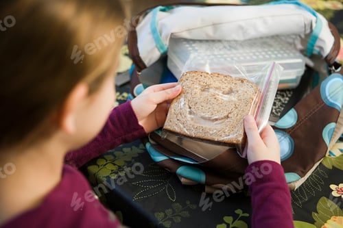 Preview: Child packing a sandwich into a backpack for school lunch