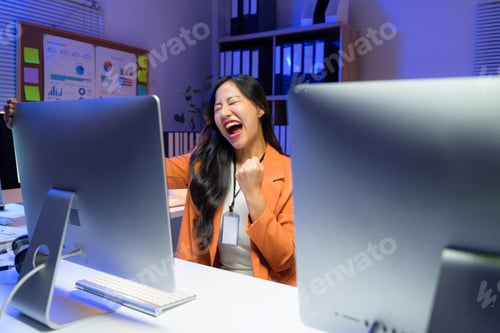 Preview: Overjoyed office worker celebrating a goal achievement while working late at night