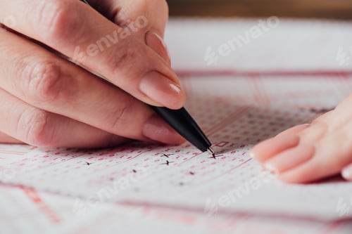 Preview: cropped view of woman marking numbers in lottery tickets with pen