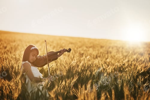 Preview: Shot of a cute little girl playing the violin while standing in a cornfield