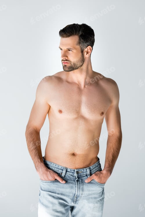 Preview: shirtless man in blue jeans standing with hands in pockets isolated on grey