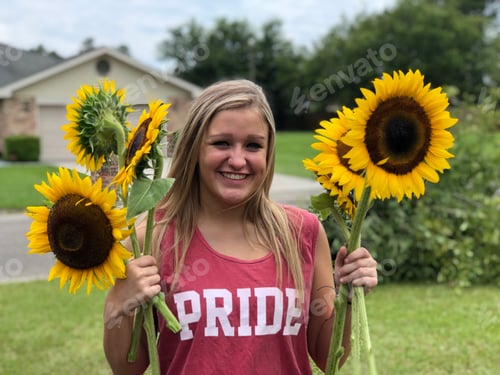 Preview: Smiling Woman Holding Sunflowers in Front of Home