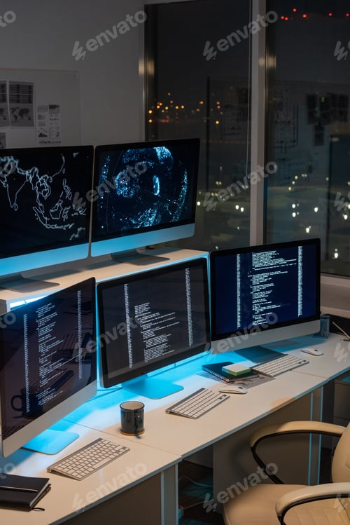 Preview: Desks with computer monitors in empty office at night time