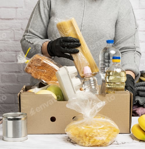 Preview: Woman in a gray sweater is packing food in a cardboard box