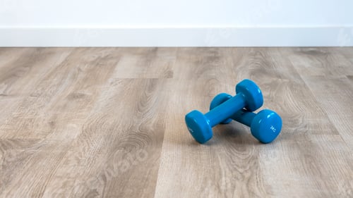 Preview: Exercise with two blue dumbbells, preparing for sports training at house indoor.