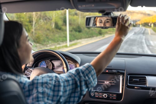 Preview: Attractive young woman driving a car, view from inside.