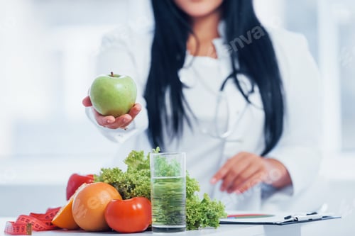 Preview: Female nutritionist in white coat holding apple in hand