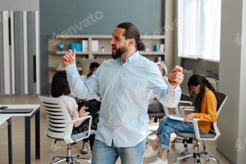 Preview: Handsome, confident businessman dancing in front of his team in modern office